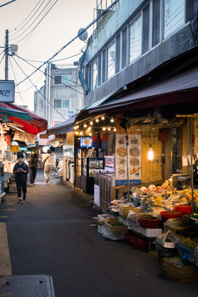 Changsin Market alley at dusk with hanging lights, food stalls, and pedestrians