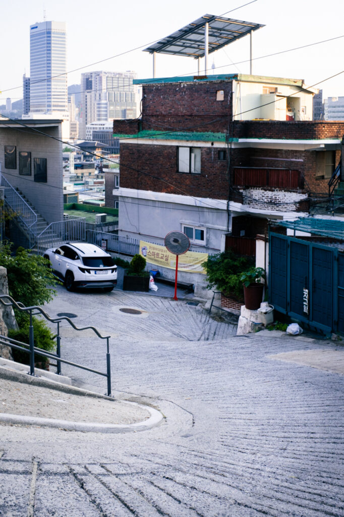 Steep winding hill in Changsin neighborhood with urban skyline in the background