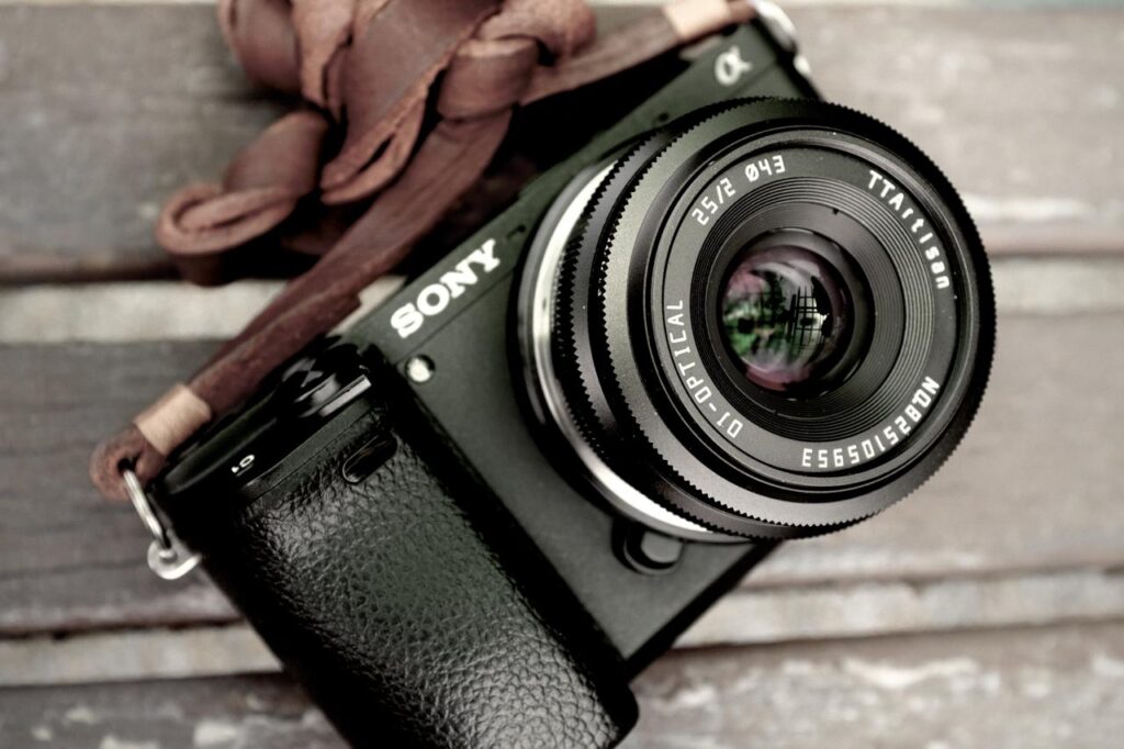 Sony A6400 mirrorless camera paired with a TTArtisan 25mm F2 lens resting on a wooden bench