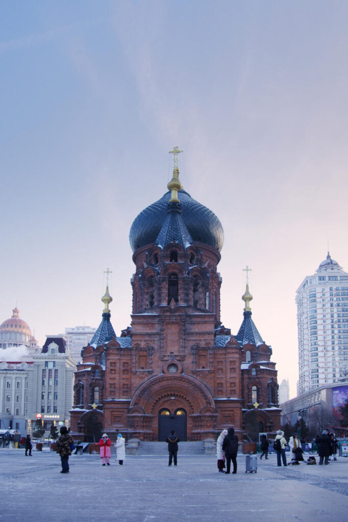 Saint Sophia Cathedral in Harbin photographed from directly in front on a winter morning, with visitors standing in the square.