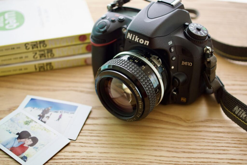 Nikon D610 DSLR fitted with a Nikkor 55mm F1.2 AI manual-focus lens on a wooden desk.