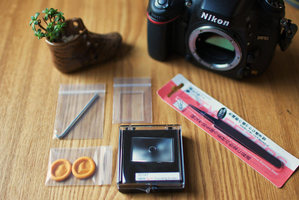Eg-Af split-prism focusing screen replacement kit with installation tools laid out beside a Nikon D610 camera body.