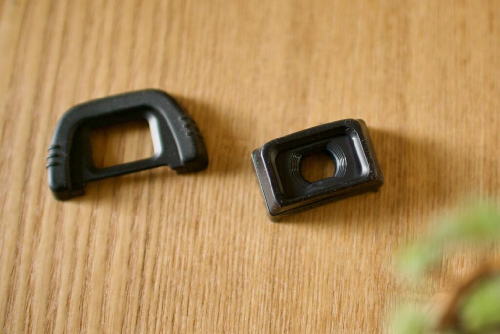 Nikon DK-21 rubber eyecup and DK-21M magnifying eyepiece placed side by side on a wooden desk.